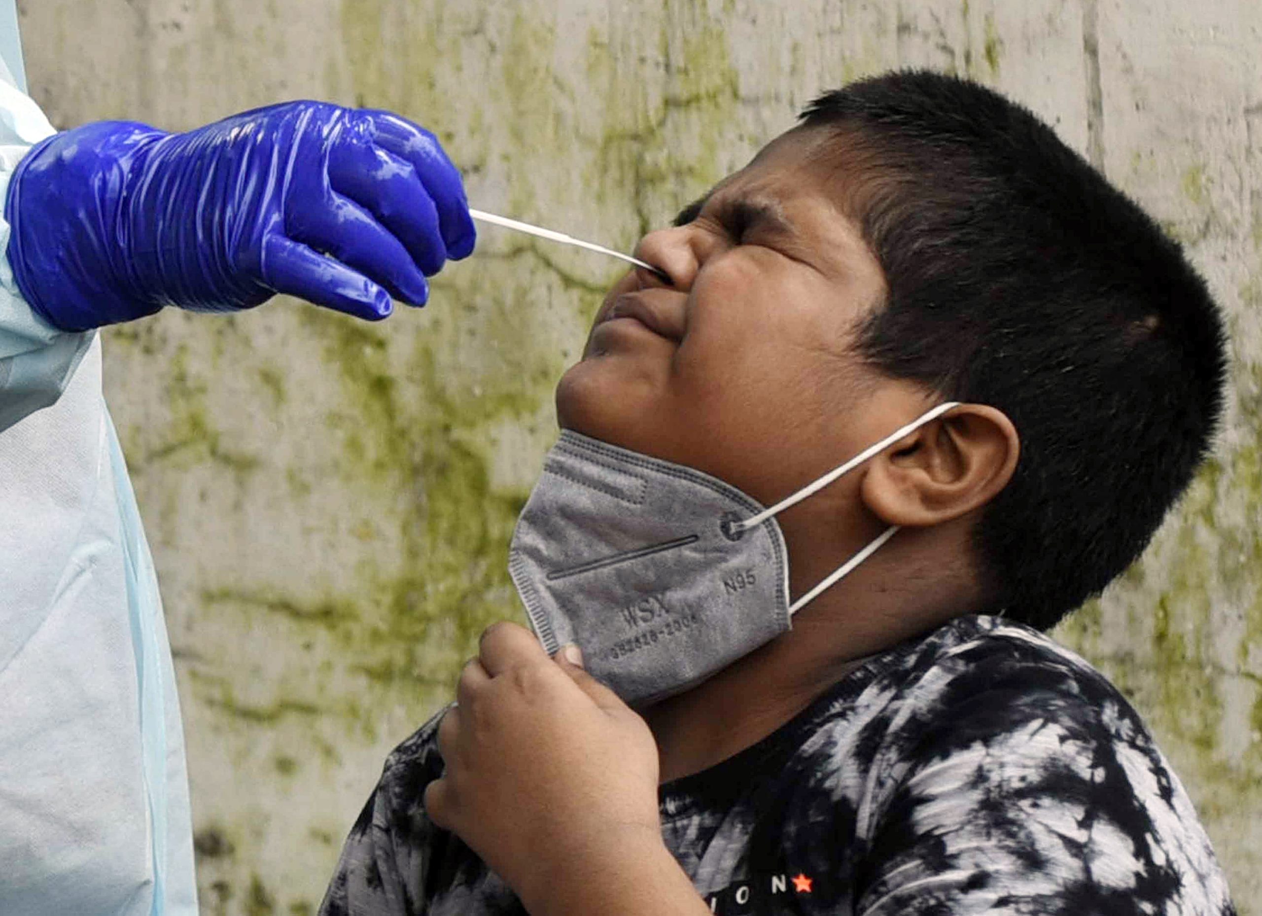 A health worker collects a nasal sample from a child for COVID-19 tests